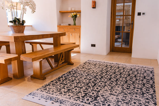 Dining room with wooden table, bench, and decorative rug.