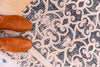 Brown leather boots standing on an Atlantic Mats recycled rug with an antiqued caption design